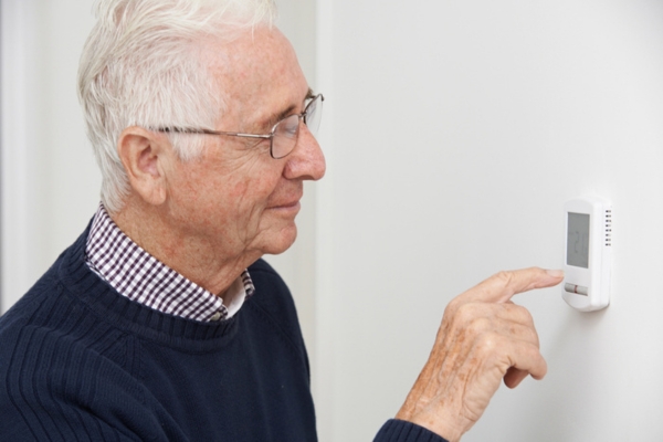 homeowner adjusting home thermostat for efficient heating
