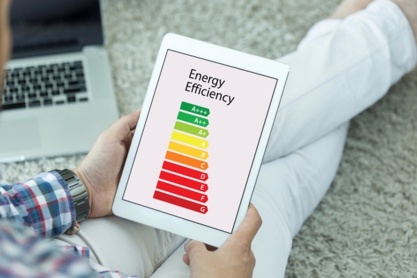 homeowner holding a smart tablet with energy efficiency meter displayed on screen