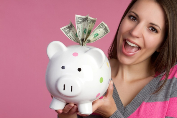 smiling woman holding a piggy bank with money on top depicting saving money with generators